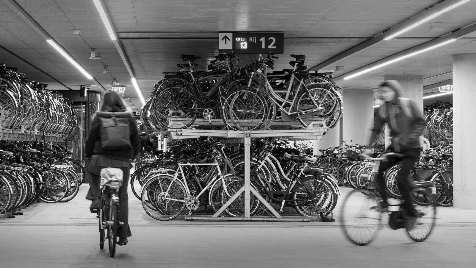 a woman riding a bike past a bunch of bikes